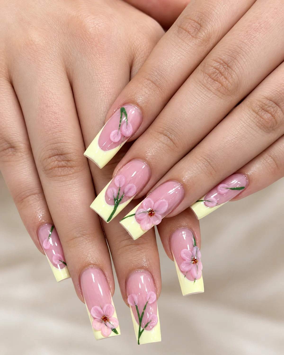 Pastel yellow French-tip nails with pink floral designs