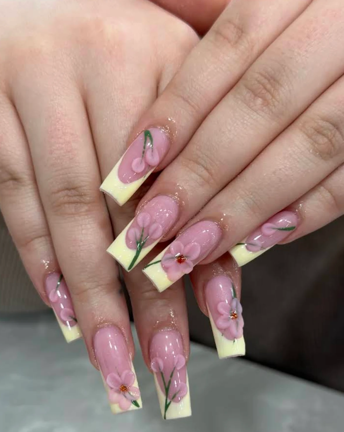 Pastel yellow French-tip nails with pink floral designs